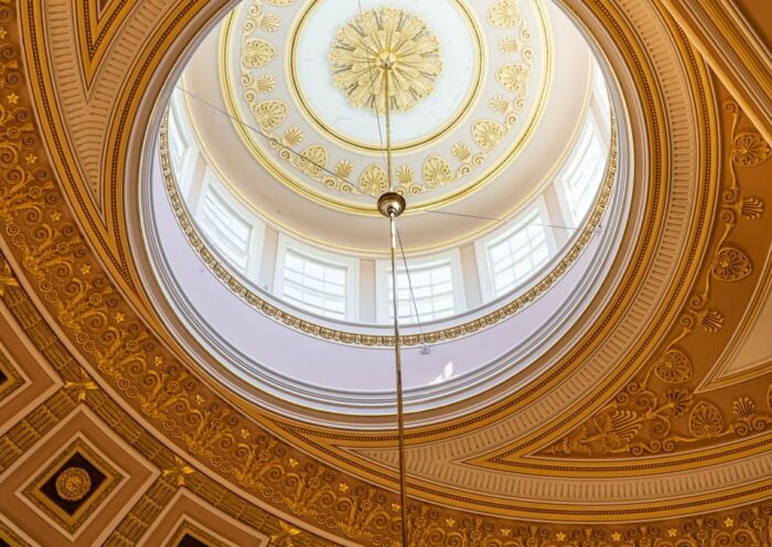 Captivating view of a domed ceiling with intricate golden patterns and sunlight from Washington, D.C