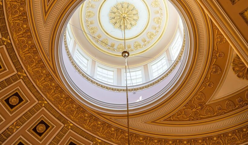 Captivating view of a domed ceiling with intricate golden patterns and sunlight from Washington, D.C
