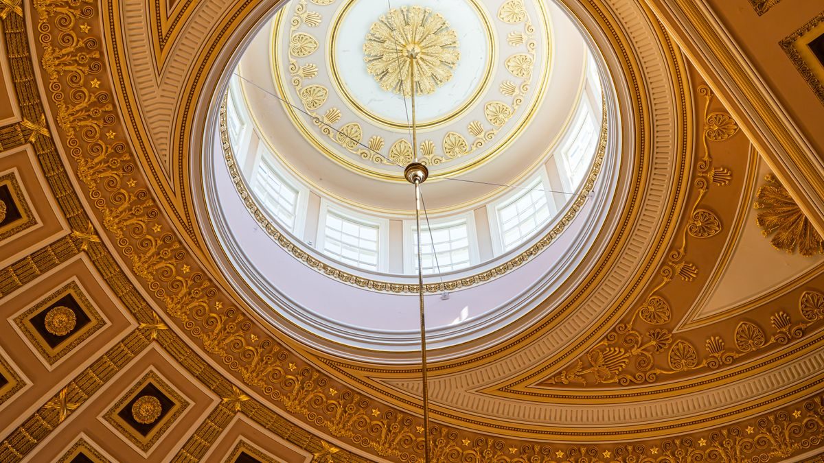 Captivating view of a domed ceiling with intricate golden patterns and sunlight from Washington, D.C