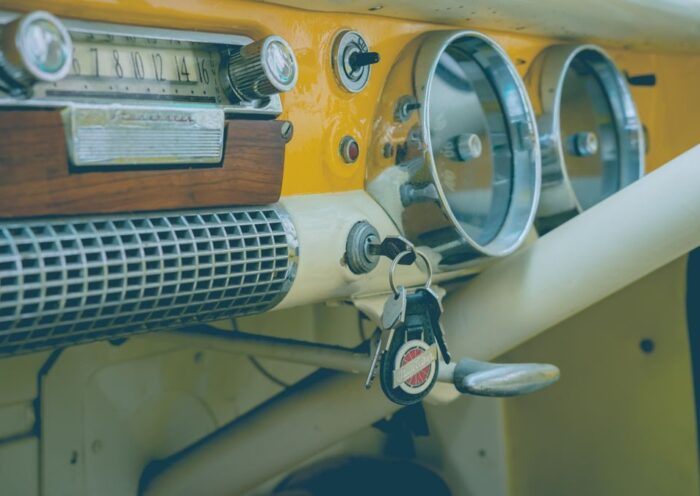 Close-up of a classic vintage car dashboard featuring an analog radio, speedometer, and keys