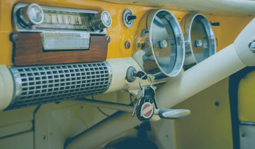 Close-up of a classic vintage car dashboard featuring an analog radio, speedometer, and keys