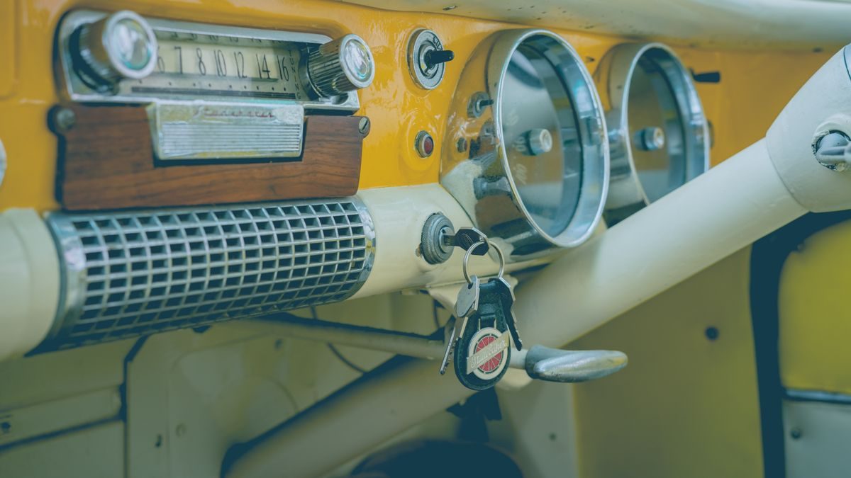 Close-up of a classic vintage car dashboard featuring an analog radio, speedometer, and keys