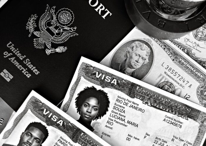 A black and white composition of a US passport, visas, and currency