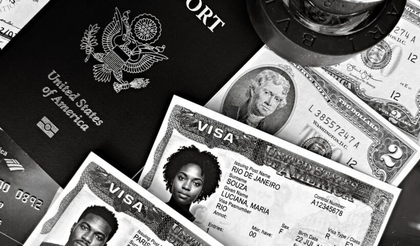 A black and white composition of a US passport, visas, and currency