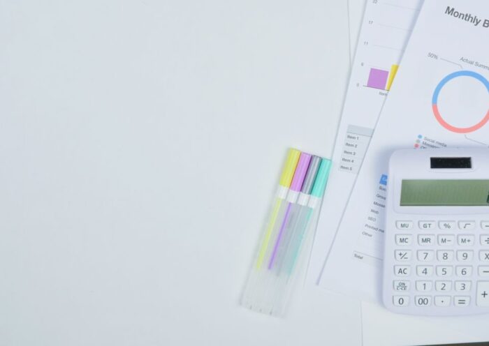 Minimalist office desk with a calculator, budget planning documents, and colorful pens