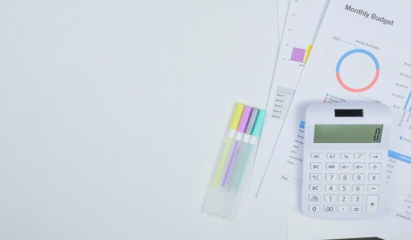Minimalist office desk with a calculator, budget planning documents, and colorful pens
