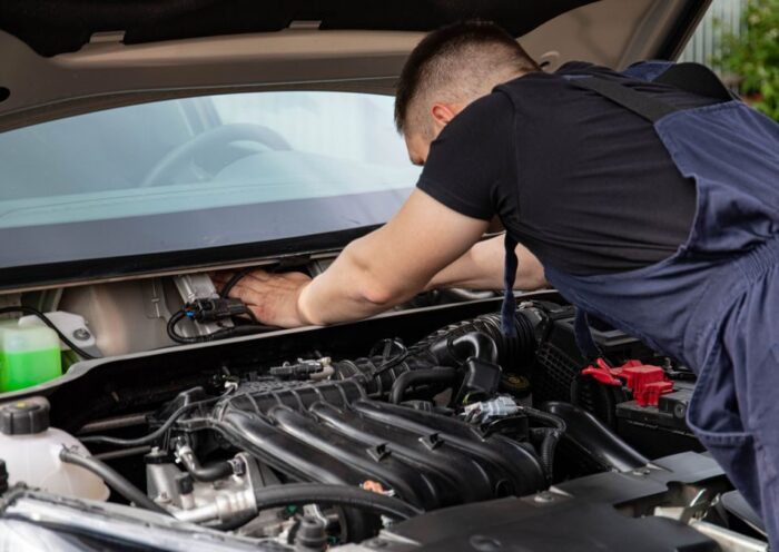 Auto mechanic performs engine maintenance on a car. Focus on hands and engine components