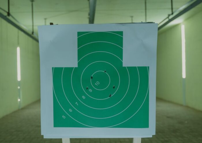 A green circle target with bullet holes at an indoor shooting range