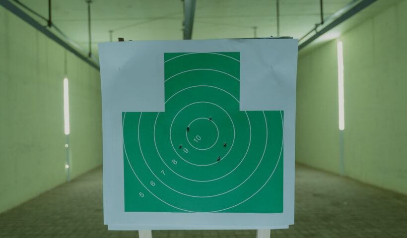 A green circle target with bullet holes at an indoor shooting range
