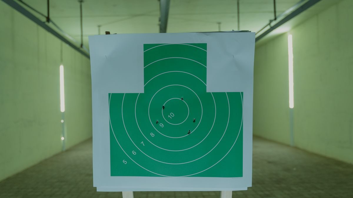A green circle target with bullet holes at an indoor shooting range