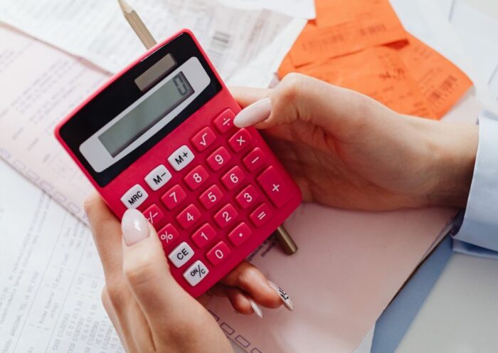 Close-up of hands holding a red calculator, managing finances with documents and receipts