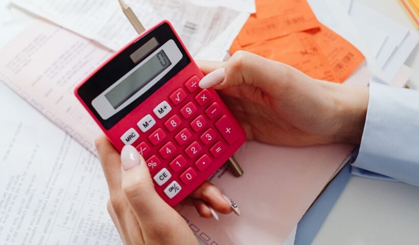 Close-up of hands holding a red calculator, managing finances with documents and receipts