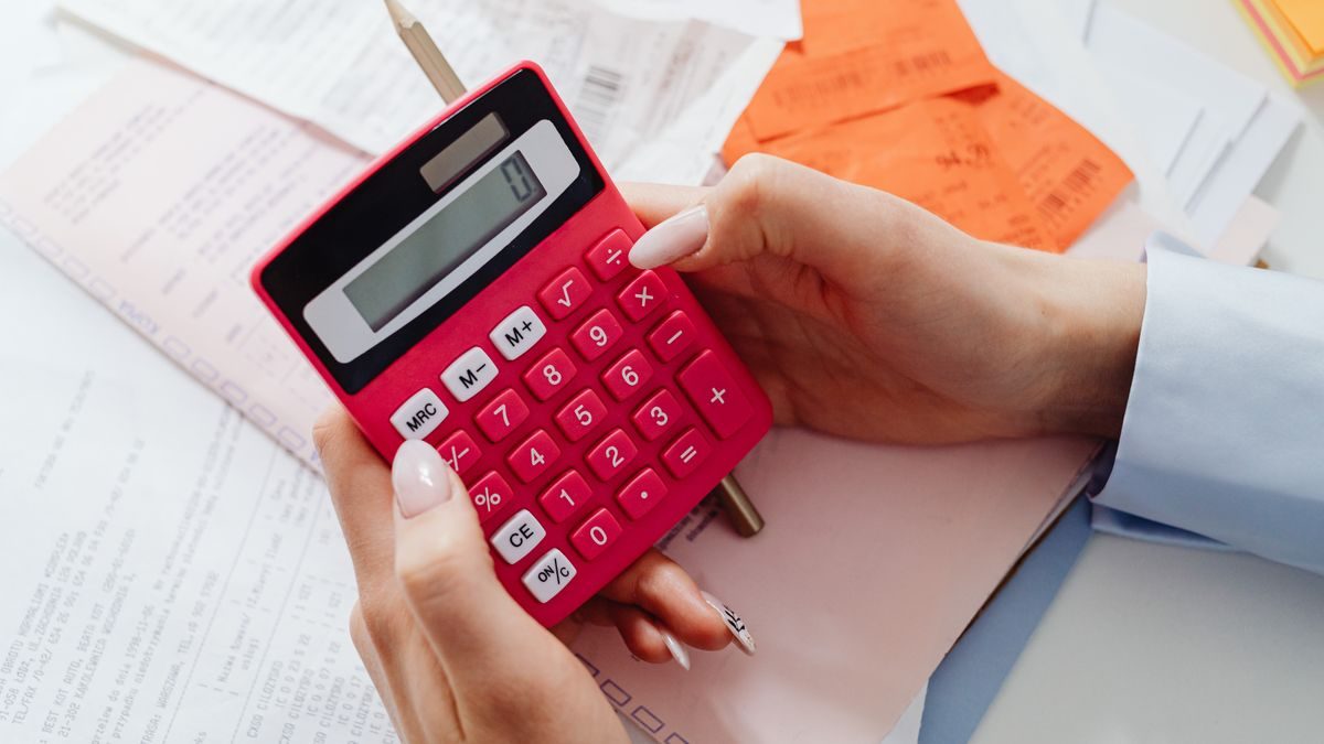 Close-up of hands holding a red calculator, managing finances with documents and receipts