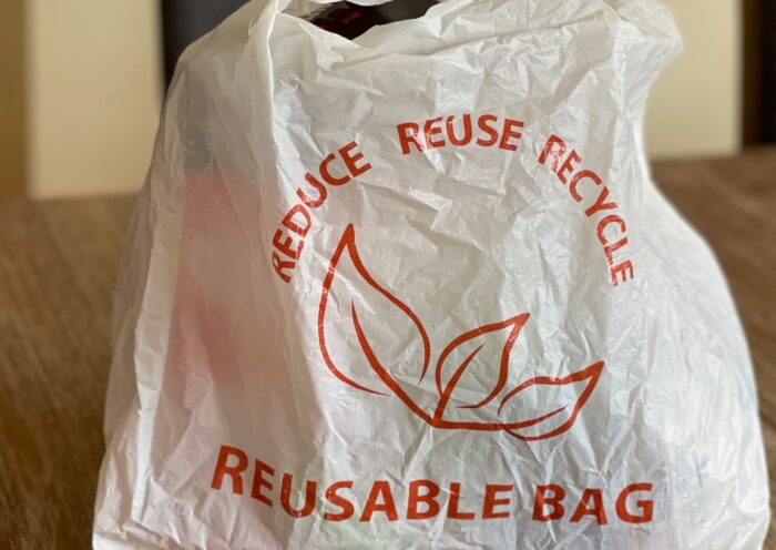 Reusable bag promoting reduce, reuse, recycle on a wooden table indoors