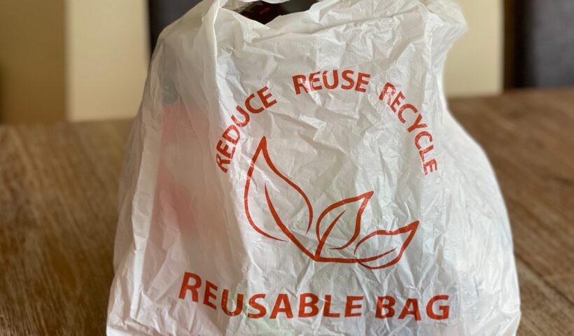 Reusable bag promoting reduce, reuse, recycle on a wooden table indoors
