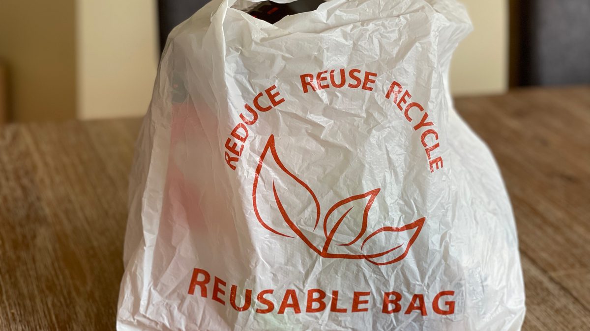 Reusable bag promoting reduce, reuse, recycle on a wooden table indoors