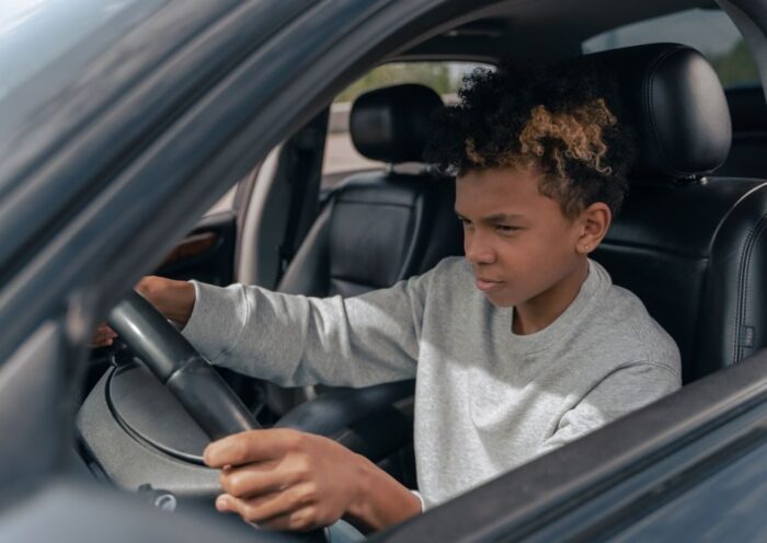 Teen boy learning to drive a car with focus and determination
