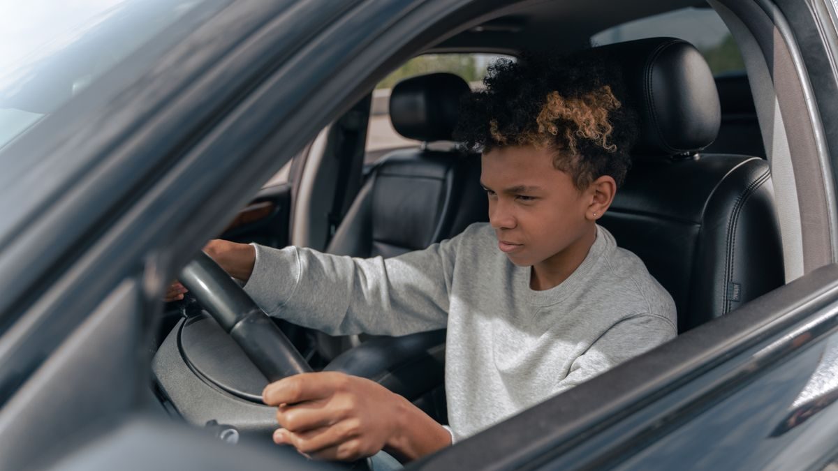 Teen boy learning to drive a car with focus and determination