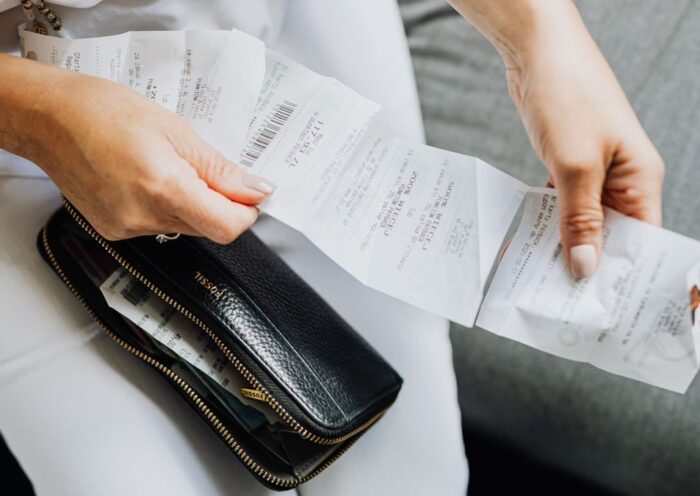 Close-up of a woman's hands managing multiple receipts taken from a black wallet