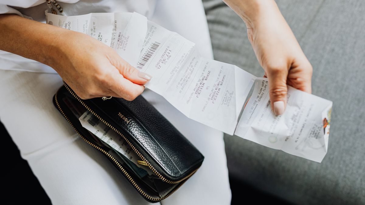 Close-up of a woman's hands managing multiple receipts taken from a black wallet