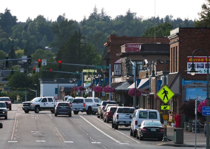 Lively urban street with cars, shops, and pedestrians during daytime