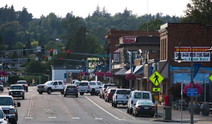 Lively urban street with cars, shops, and pedestrians during daytime