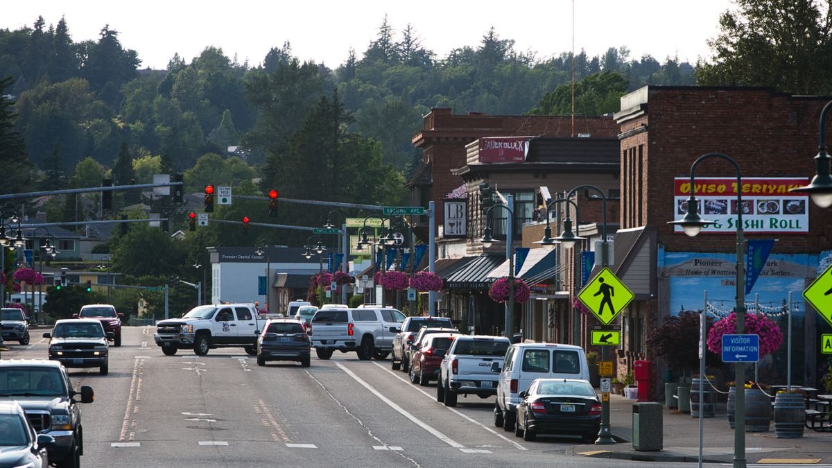 Lively urban street with cars, shops, and pedestrians during daytime