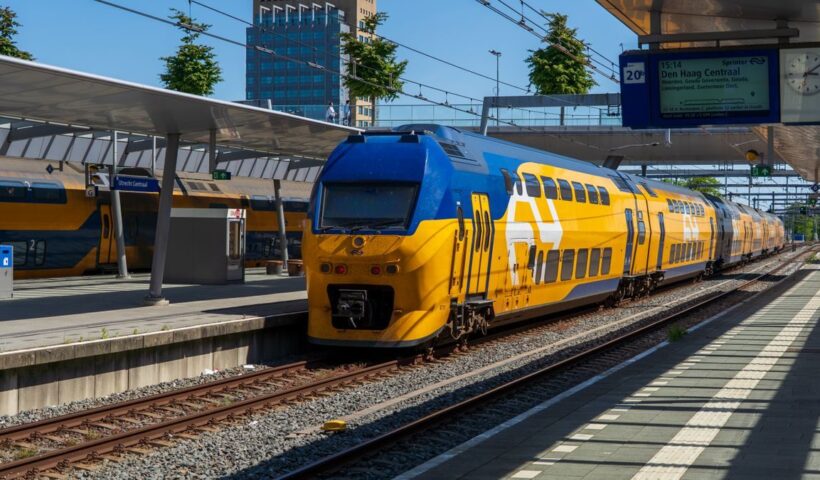 Colorful blue and yellow train arriving at Utrecht Central Station in the Netherlands on a sunny day