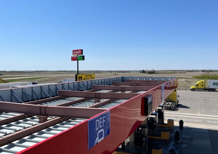Aerial view of a truck stop with gas station and parking lot under a clear blue sky