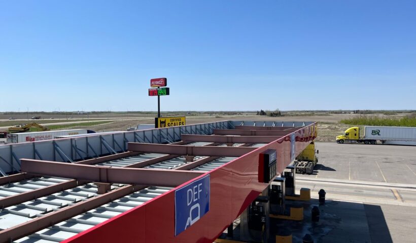 Aerial view of a truck stop with gas station and parking lot under a clear blue sky