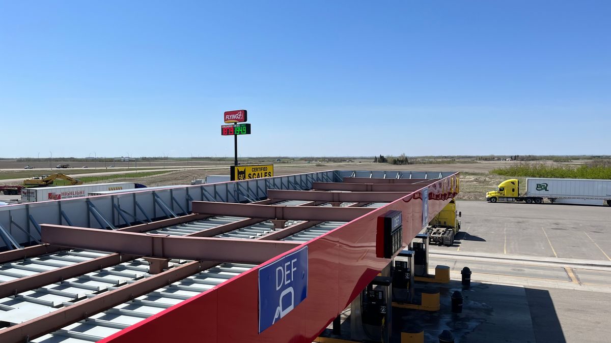 Aerial view of a truck stop with gas station and parking lot under a clear blue sky