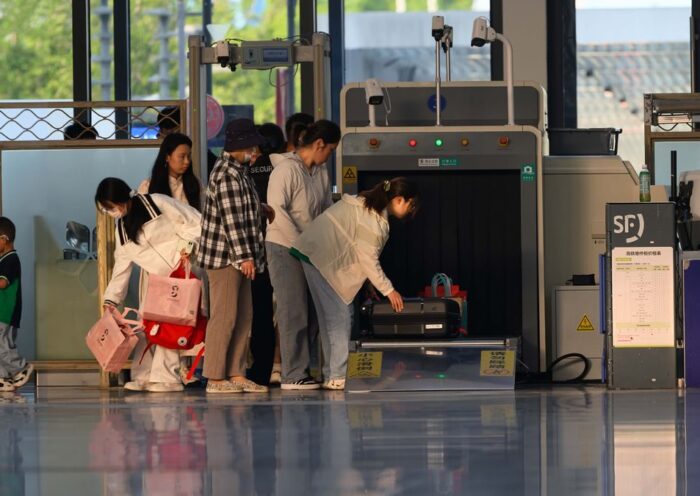 Travelers undergo security screening at an airport terminal