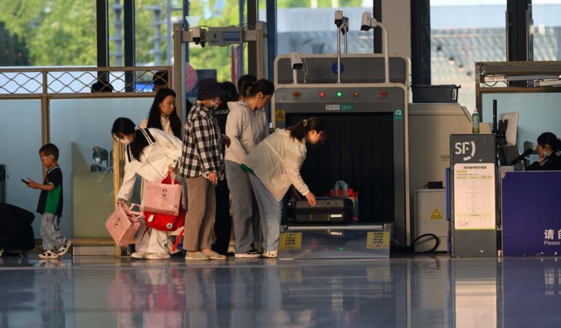 Travelers undergo security screening at an airport terminal